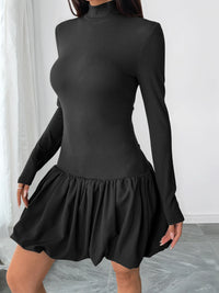Black ribbed long-sleeve dress with a skirt on a plain background