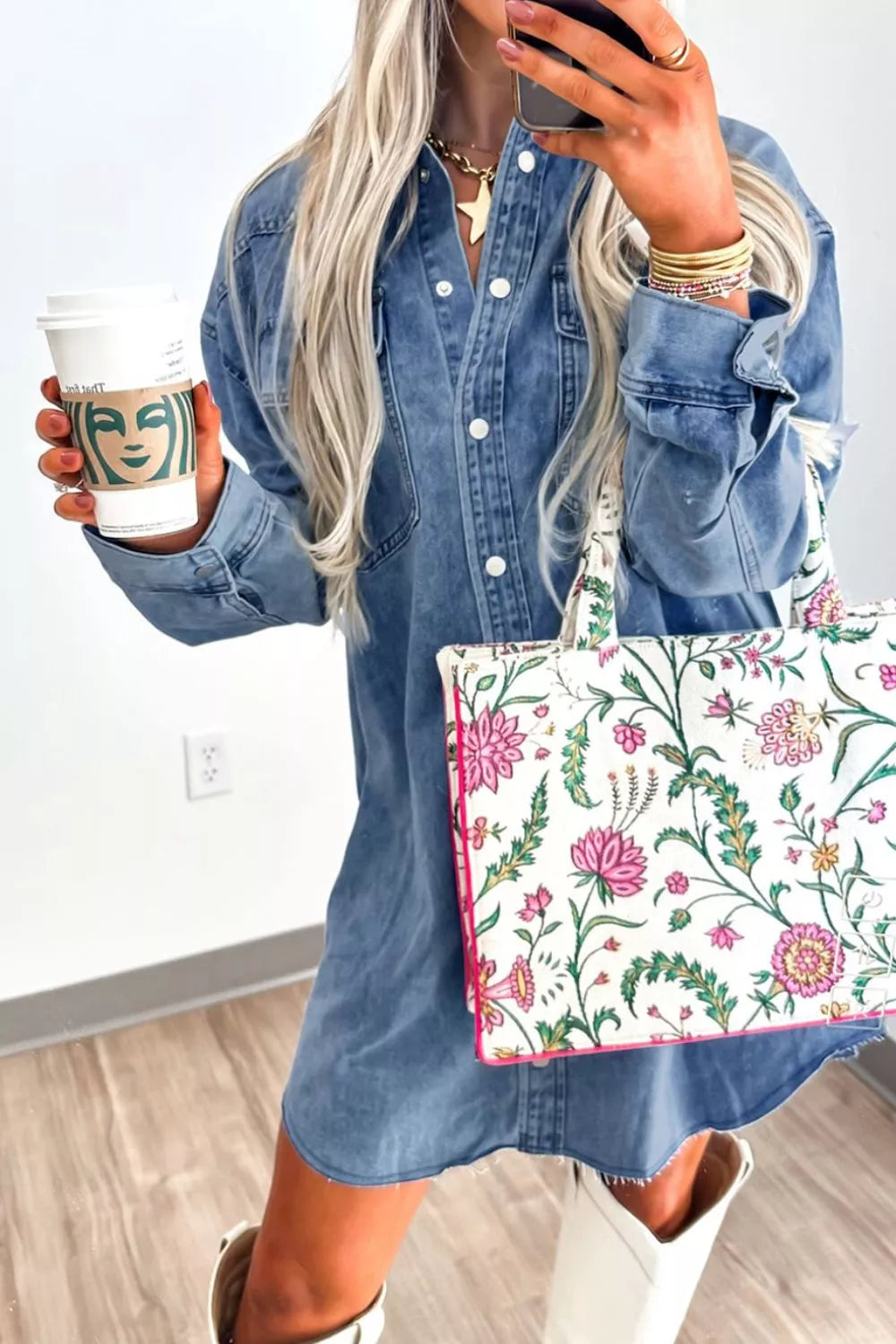 Person holding a floral bag and a Starbucks cup indoors