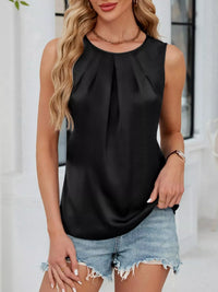 Woman wearing a black sleeveless top and denim shorts outdoors.