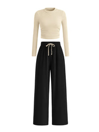 Beige long-sleeve top and black wide-leg pants on a white background