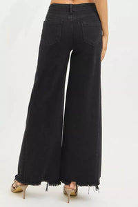 Black wide-leg jeans worn by a person on a white background
