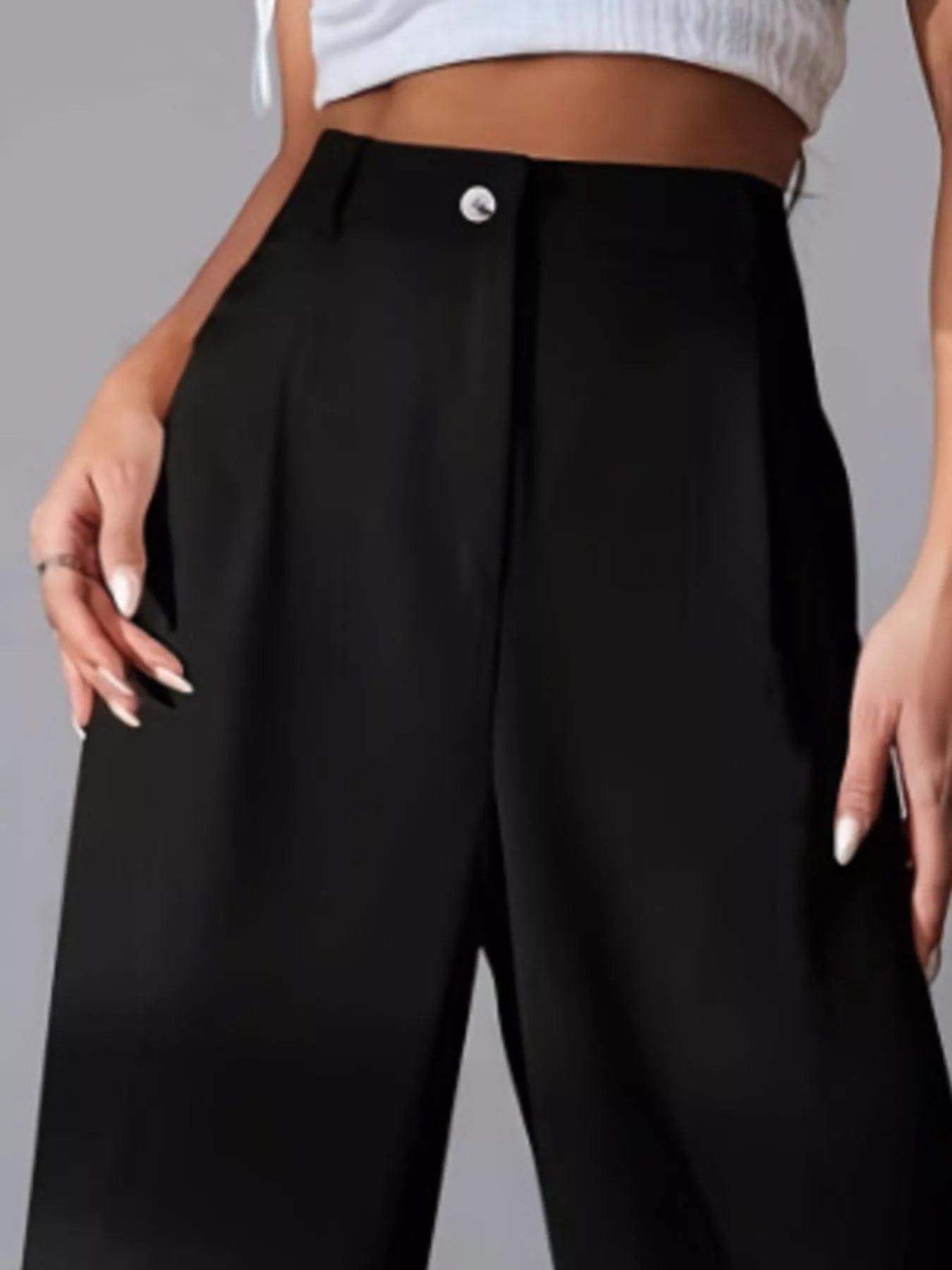 Black high-waisted pants worn by a person on a gray background
