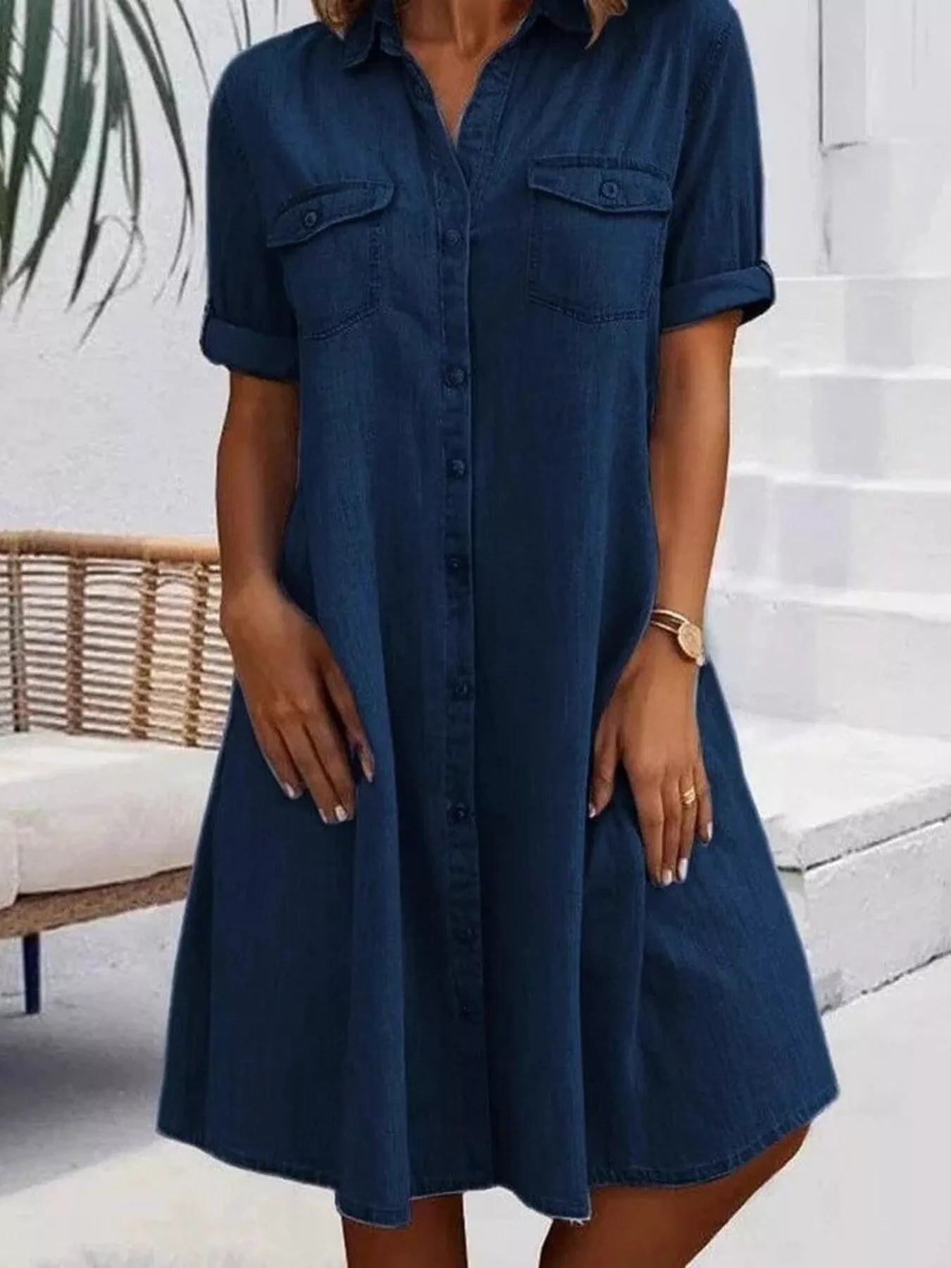 Woman wearing a blue denim dress standing on a white staircase.
