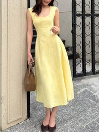 Woman in a yellow dress standing on a street.