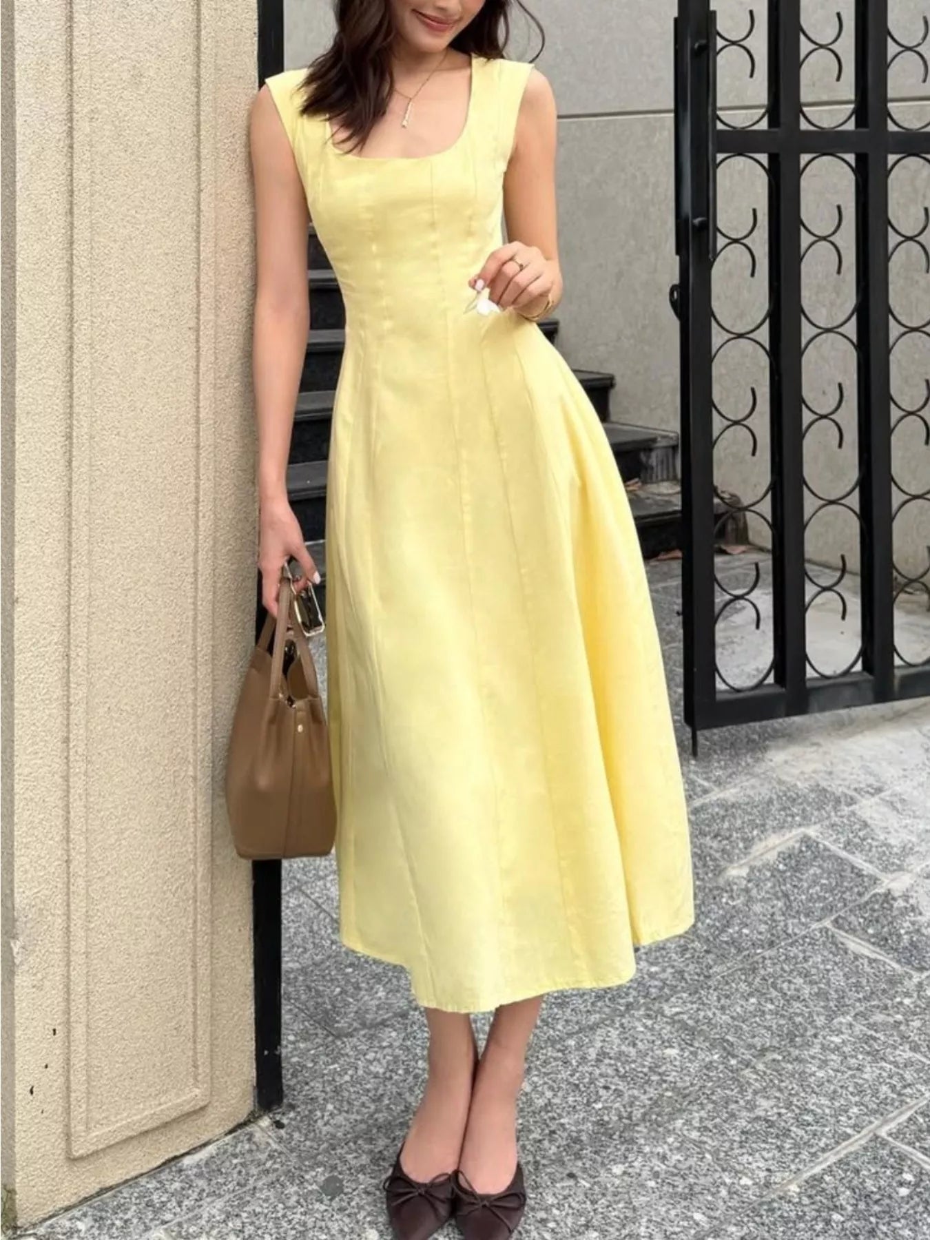 Woman in a yellow dress standing on a street.