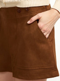 Brown shorts worn by a person with a beige sweater, showing a close-up of the shorts.