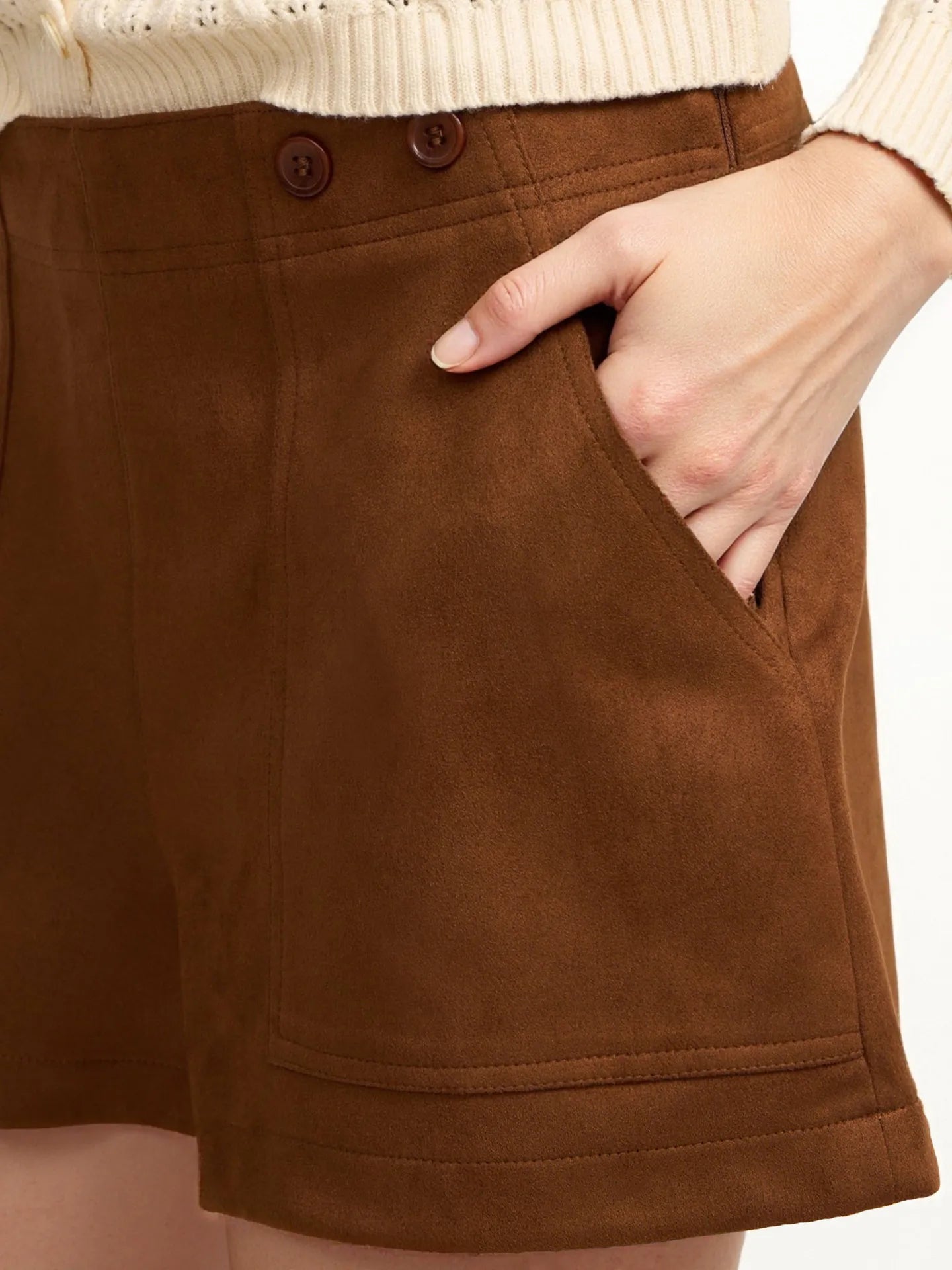 Brown shorts worn by a person with a beige sweater, showing a close-up of the shorts.