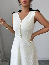Woman wearing a white sleeveless dress with buttons against a neutral background
