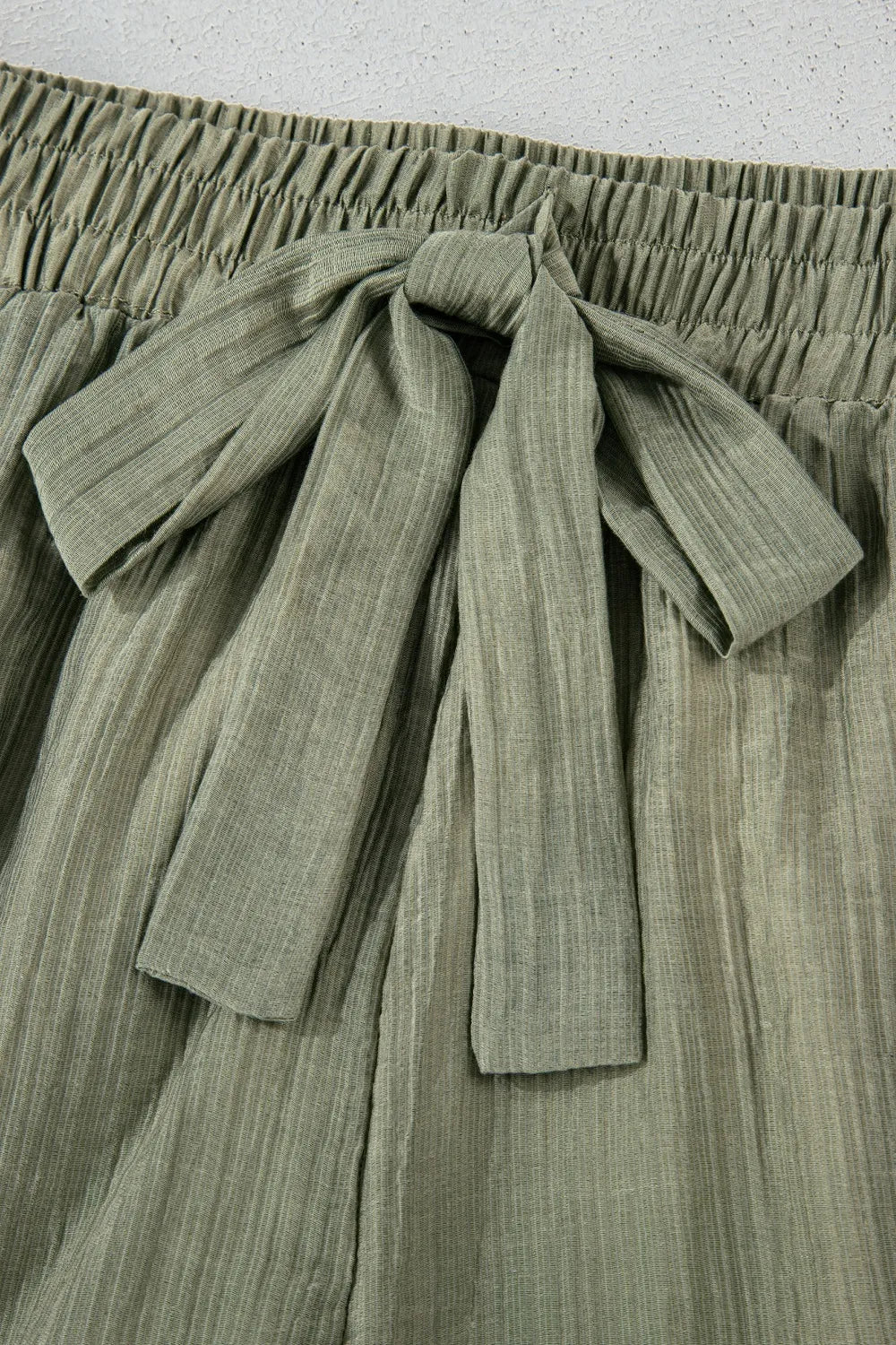 Green pleated skirt with a tie waist on a light gray background