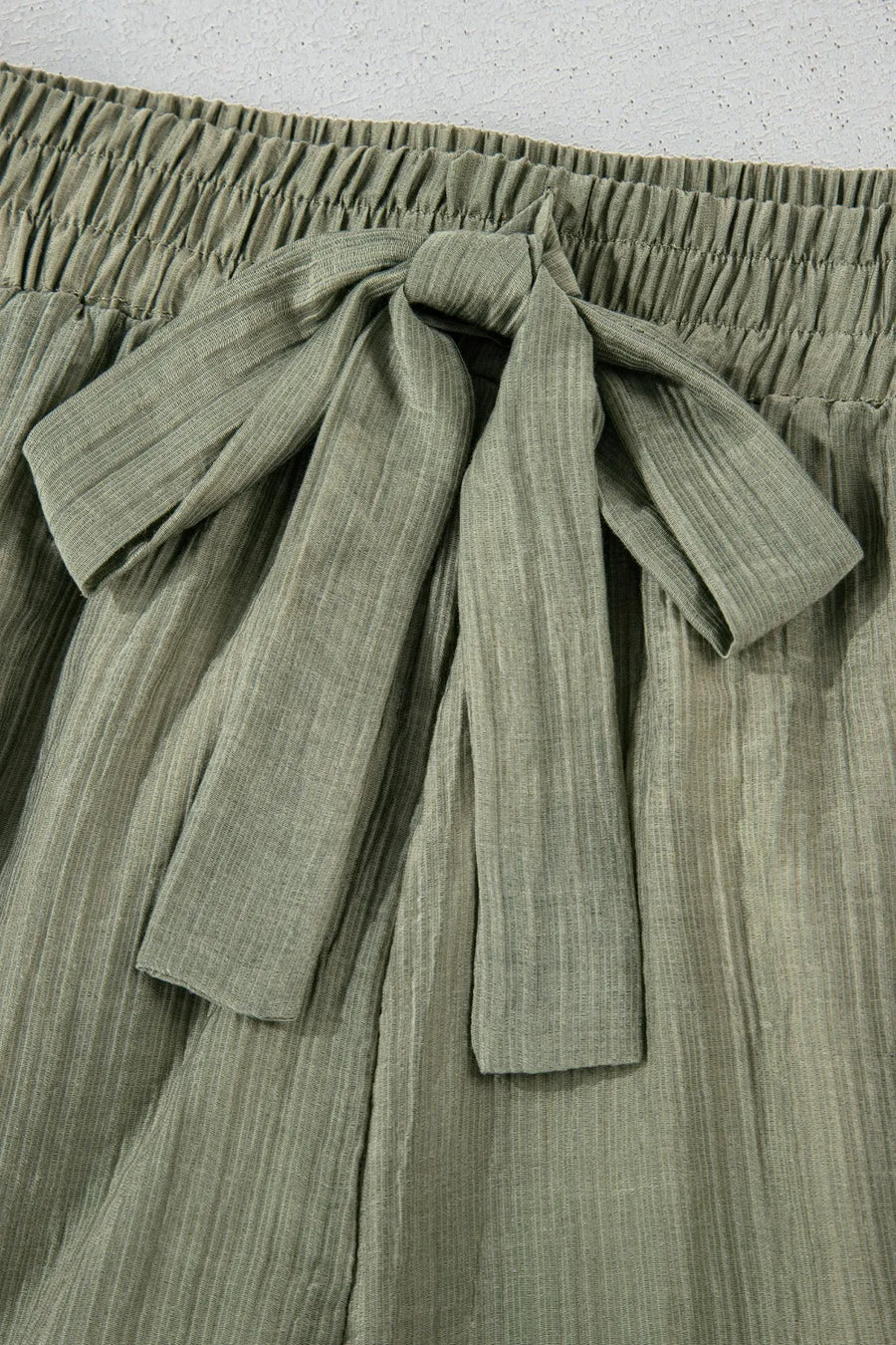 Green pleated skirt with a tie waist on a light gray background