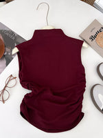 Maroon sleeveless top on a hanger with books and glasses in the background