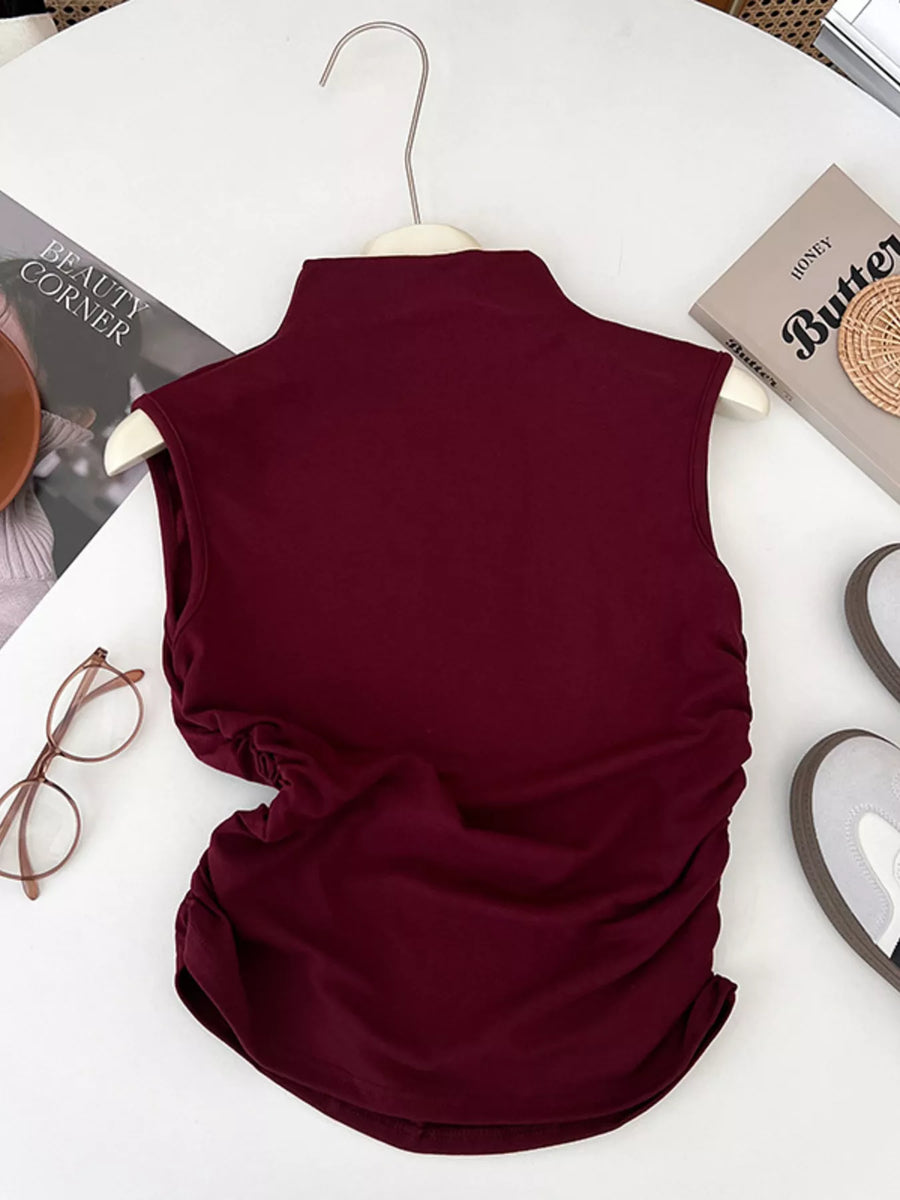 Maroon sleeveless top on a hanger with books and glasses in the background