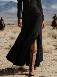 Person wearing a black dress and brown boots in a desert setting with mountains in the background.