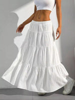 Person wearing a white tiered skirt and white top on a plain background