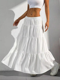 Person wearing a white tiered skirt and white top on a plain background