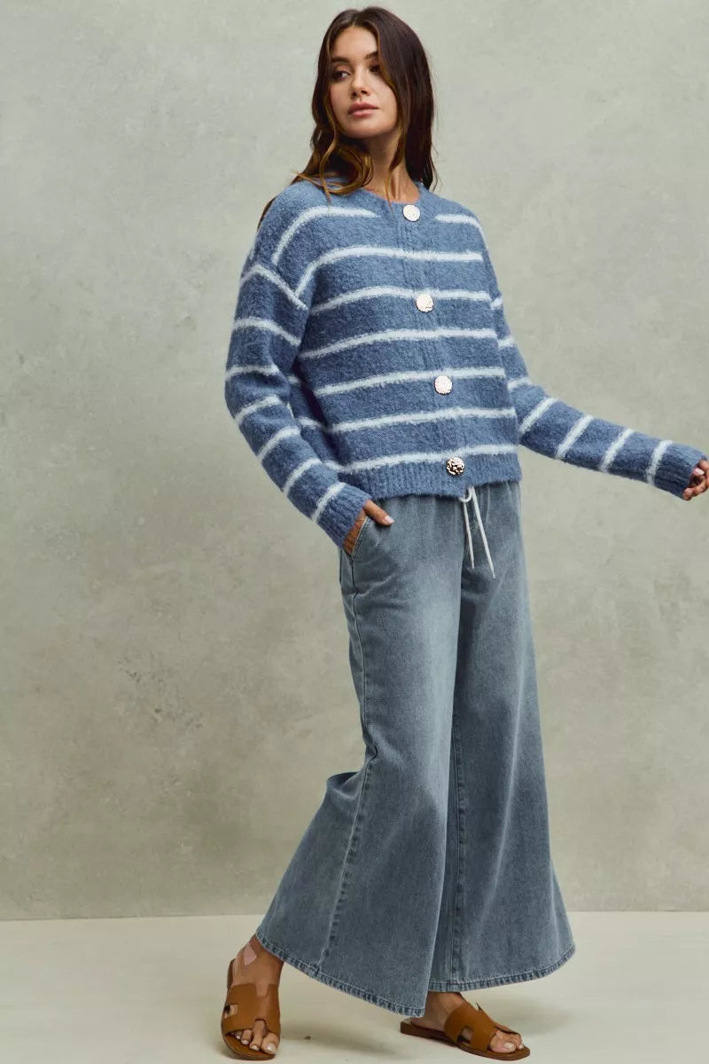 Woman wearing a blue striped sweater and jeans against a plain background