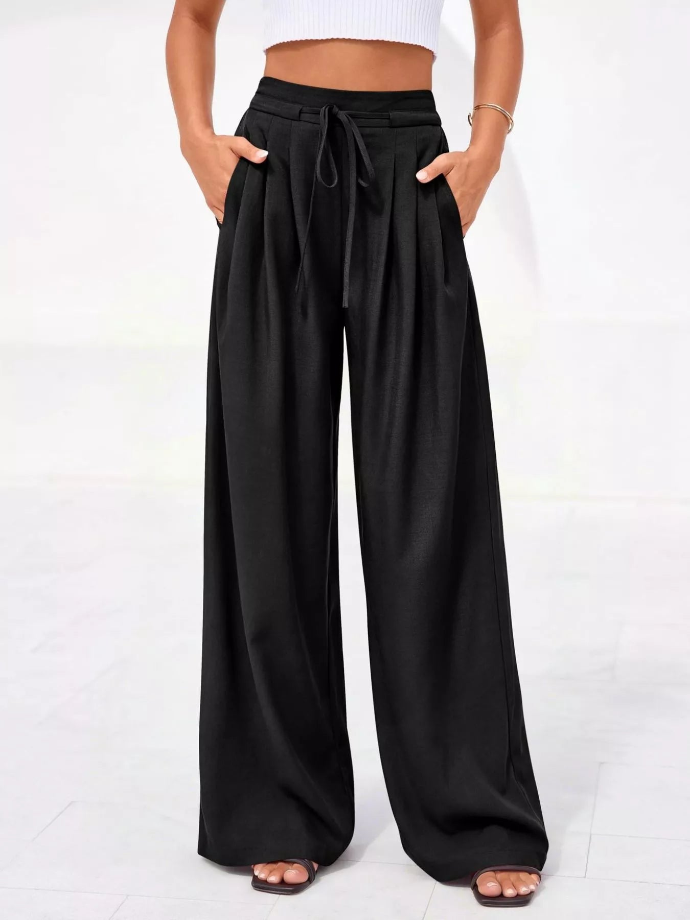 Black wide-leg pants worn by a person on a white background