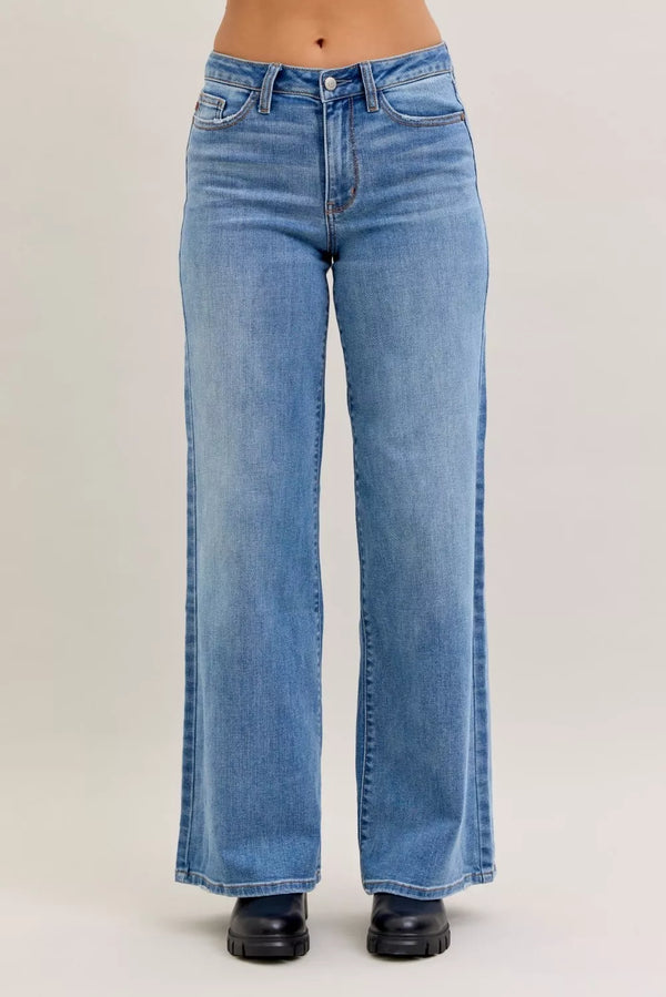 Blue jeans worn by a person on a plain background