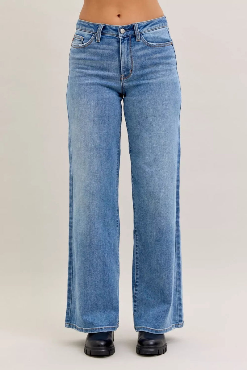 Blue jeans worn by a person on a plain background