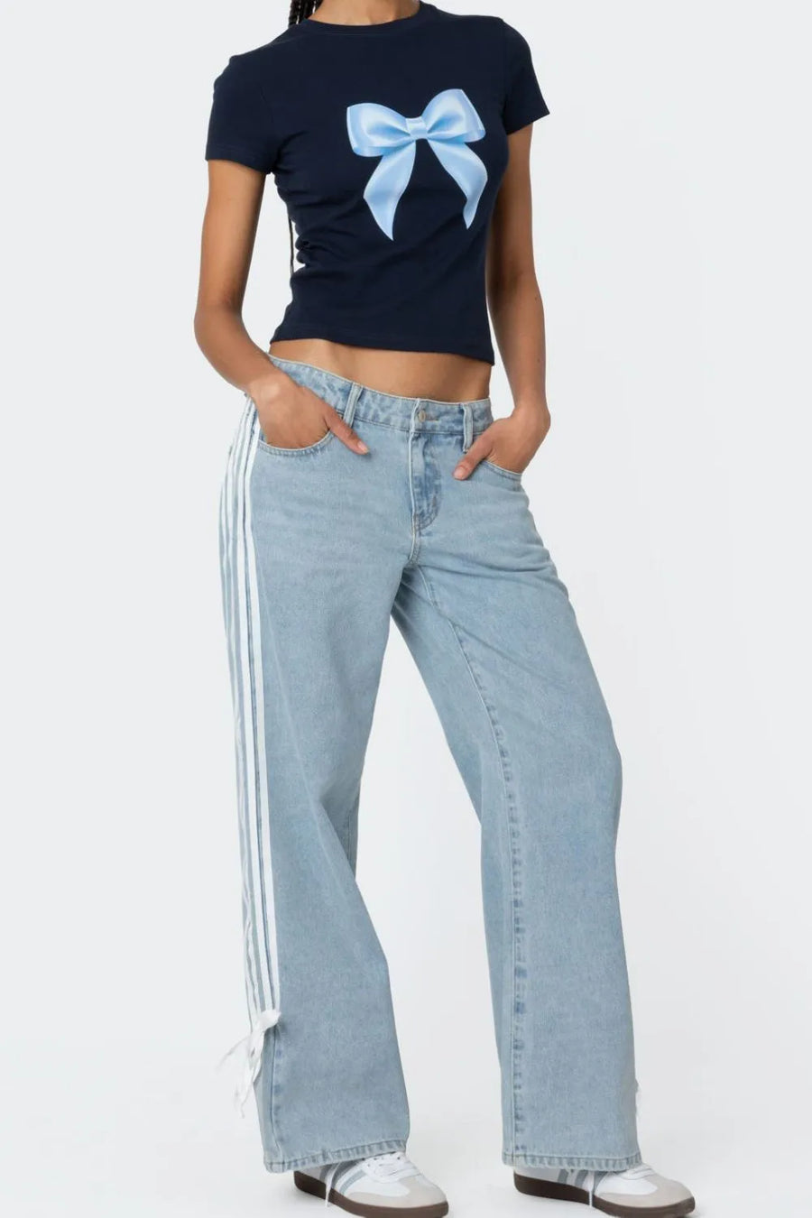 Person wearing a black t-shirt with a blue bow design and light blue jeans on a white background