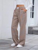 Person wearing brown plaid pants standing on a stone pavement.