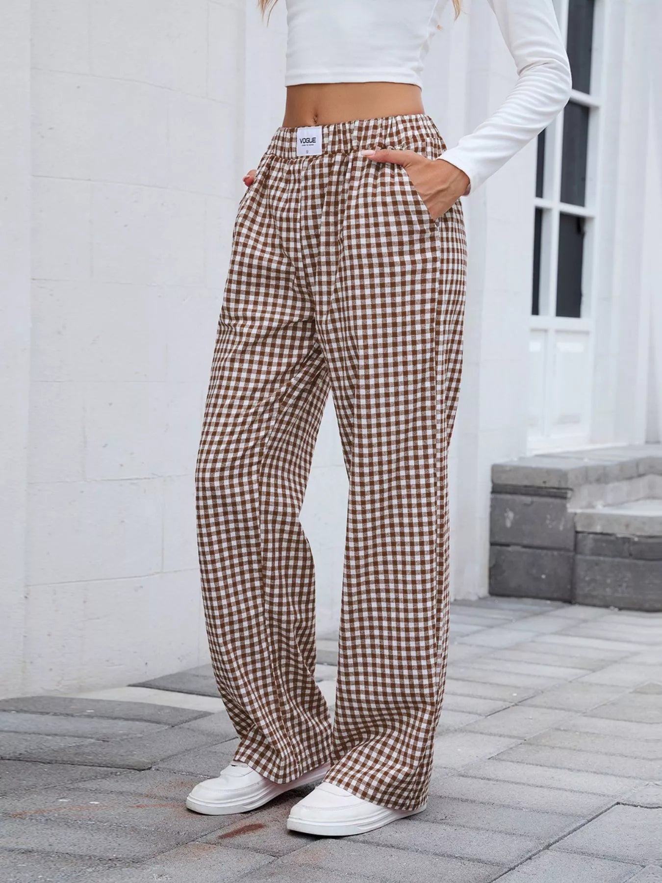 Person wearing brown plaid pants standing on a stone pavement.