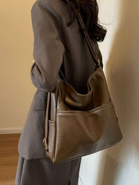 Person wearing a brown leather handbag against a plain background