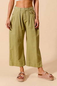 Person wearing green wide-leg pants on a beige background