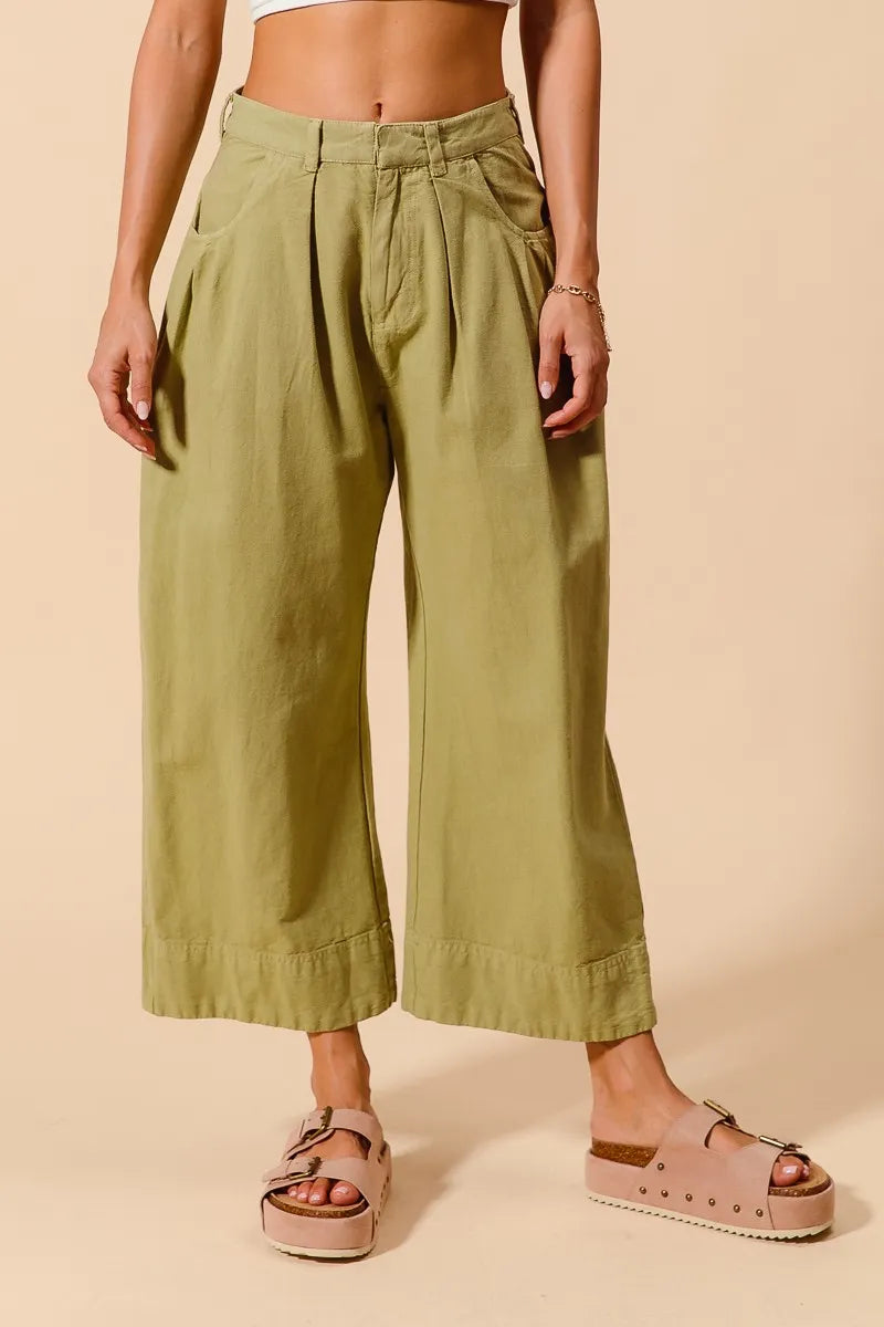 Person wearing green wide-leg pants on a beige background