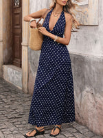 Woman in a navy blue polka dot dress holding a straw bag on a street.