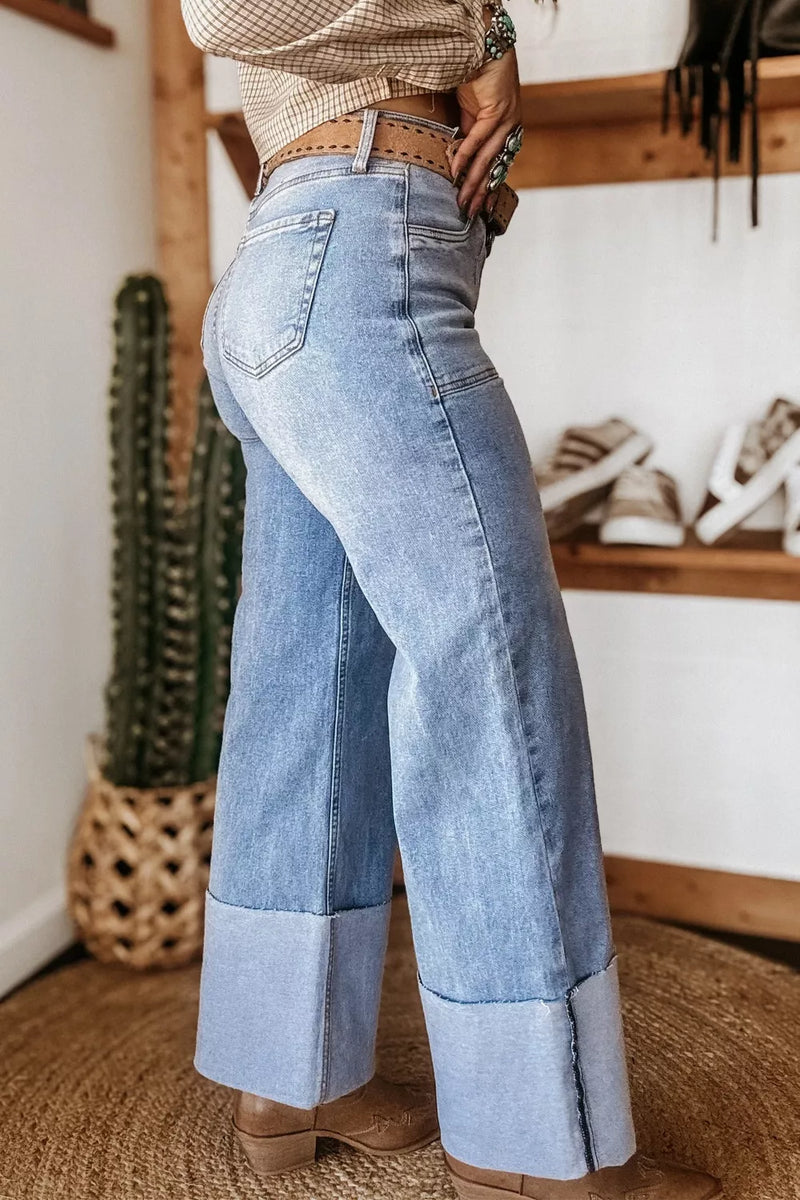 Person wearing high-waisted blue jeans in a room with a cactus and shoes in the background.