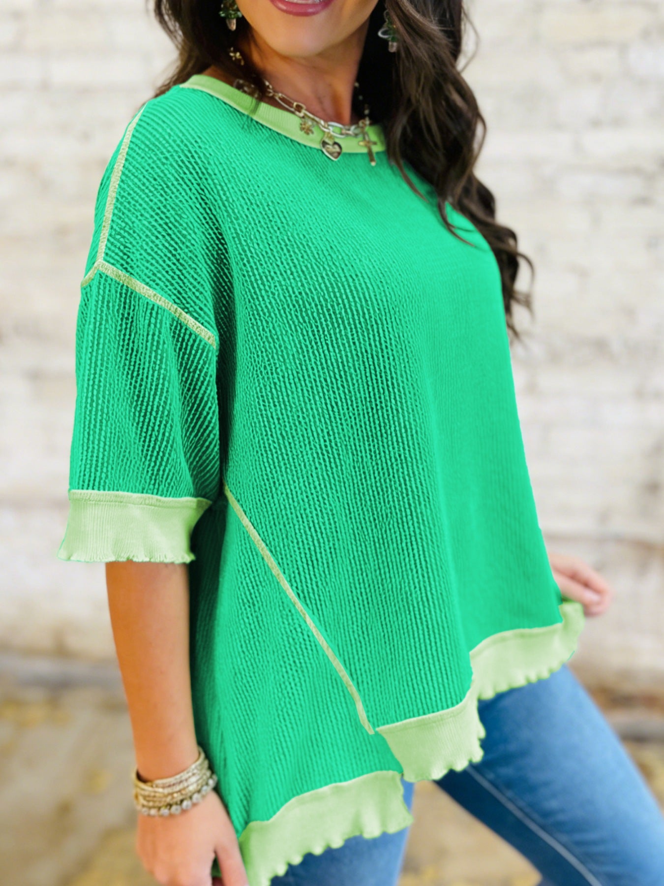 Woman wearing a green poncho with light green trim against a blurred background