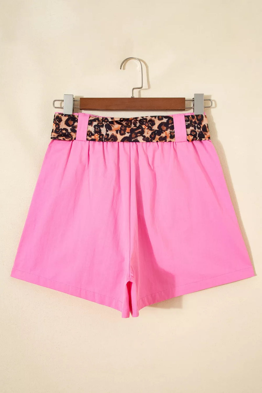 Pink shorts with a leopard print waistband on a beige background