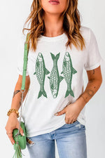 Woman wearing a white t-shirt with green fish graphics, holding a green purse.