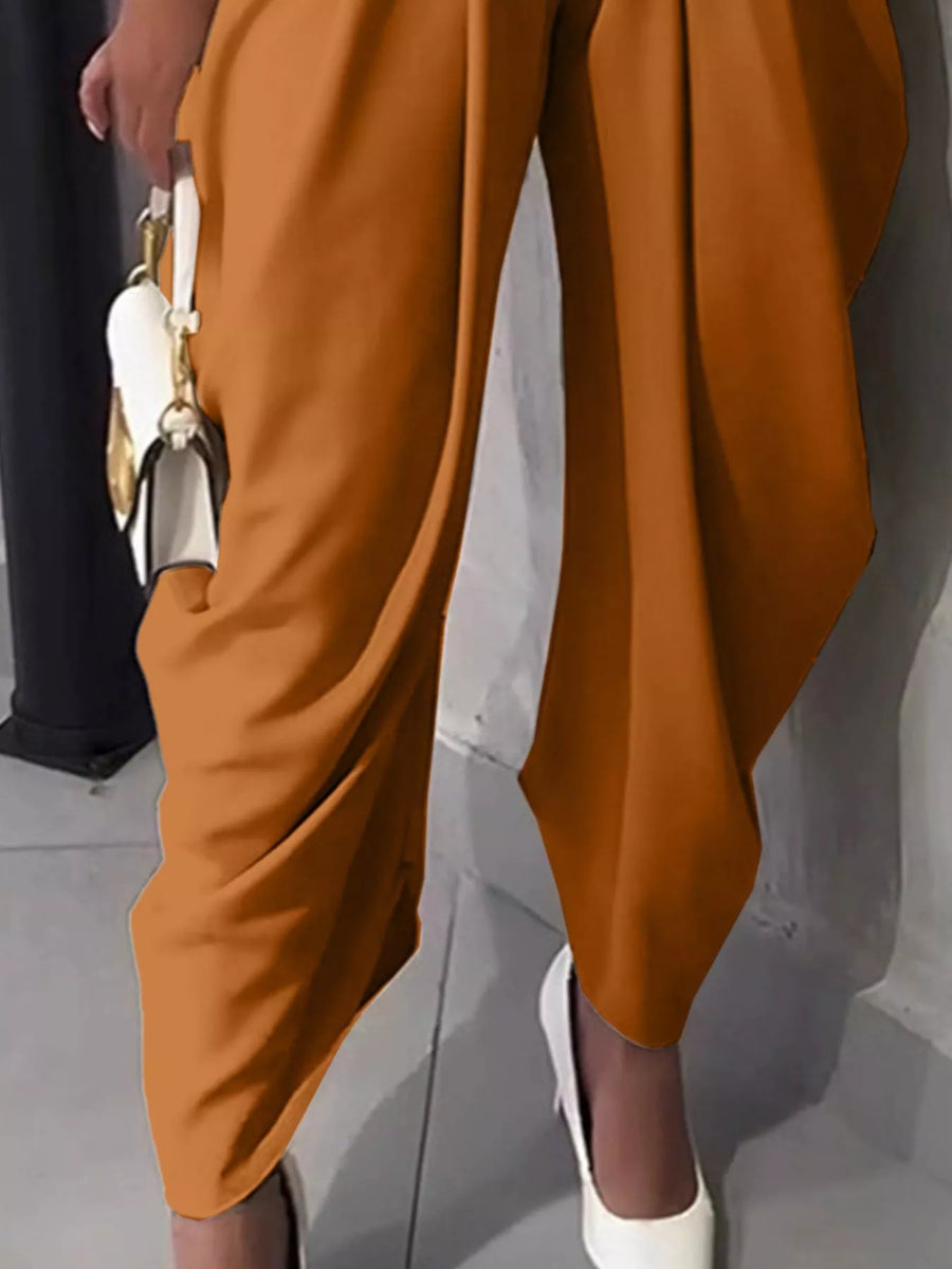 Brown pants being worn with a white shoe on a neutral background