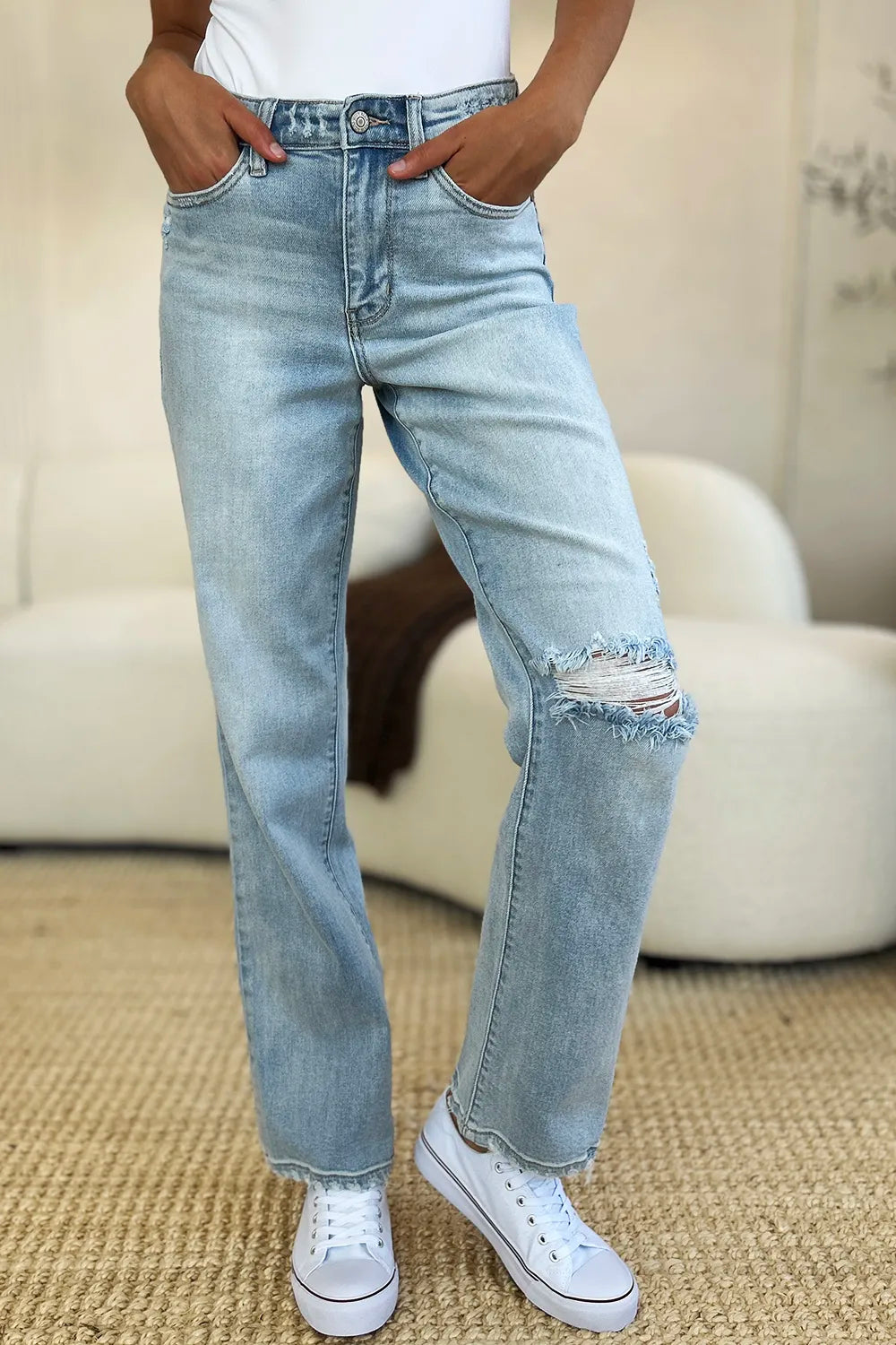 Person wearing light blue jeans with a slight distressed look, standing on a carpeted floor.