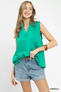 Woman wearing a green sleeveless top and denim shorts on a white background