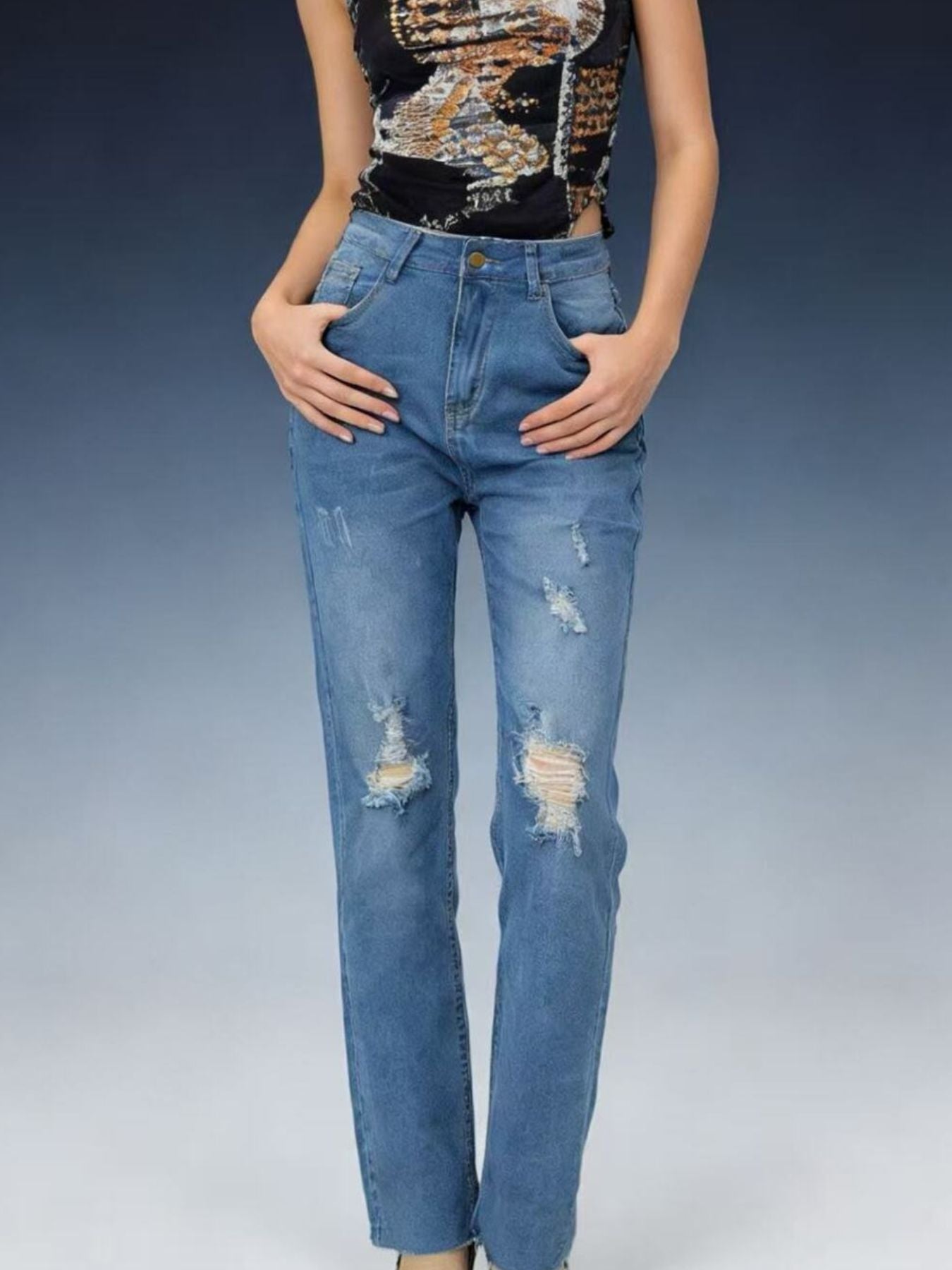 Person wearing distressed blue jeans on a gradient background