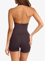 Woman wearing a dark brown halter top and shorts on a white background