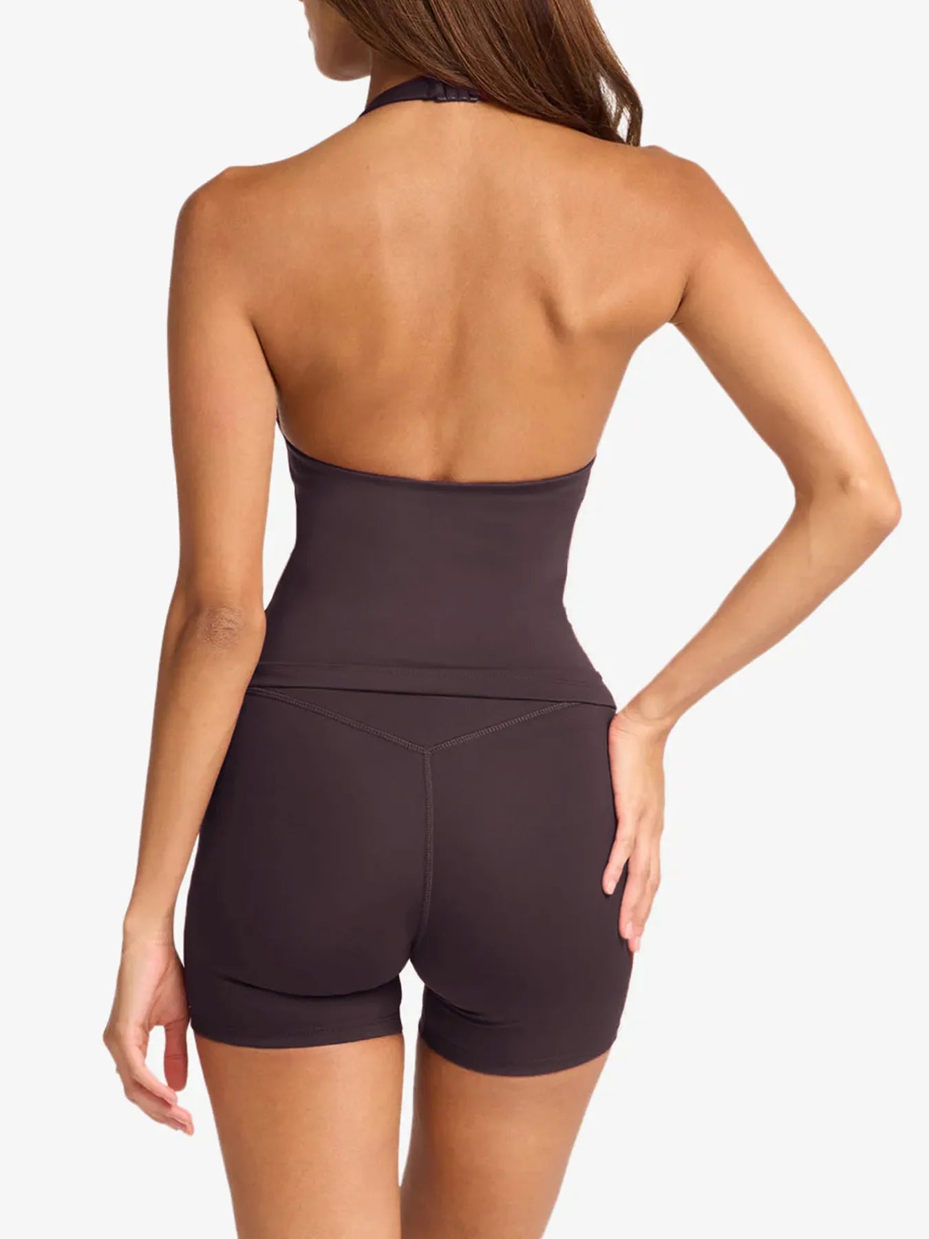 Woman wearing a dark brown halter top and shorts on a white background