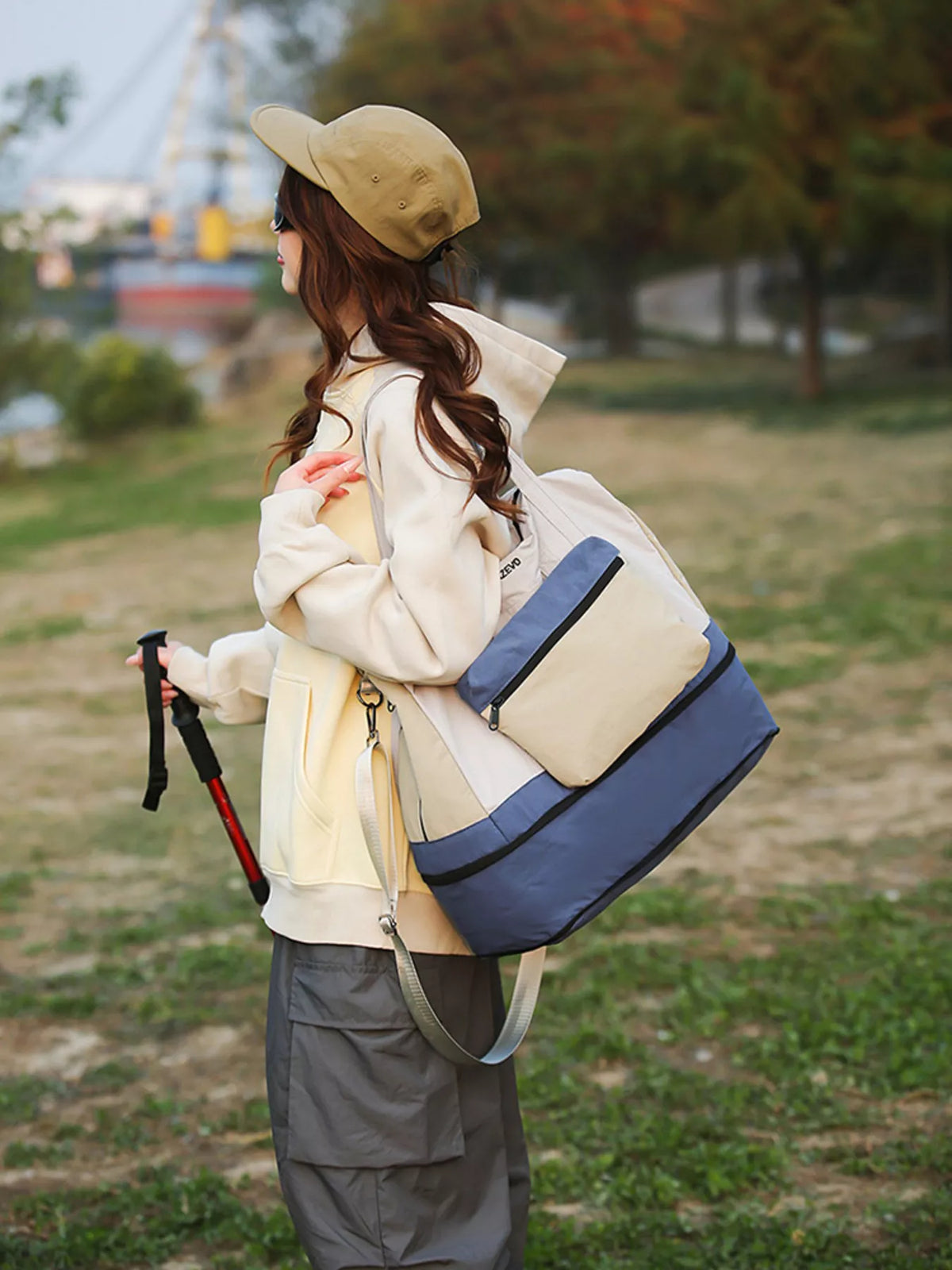 Person holding a large blue and beige bag outdoors with a blurred background