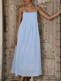 Woman wearing a light blue dress standing in front of a wooden door.