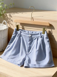 Blue and white striped shorts on a wooden hanger against a wooden background
