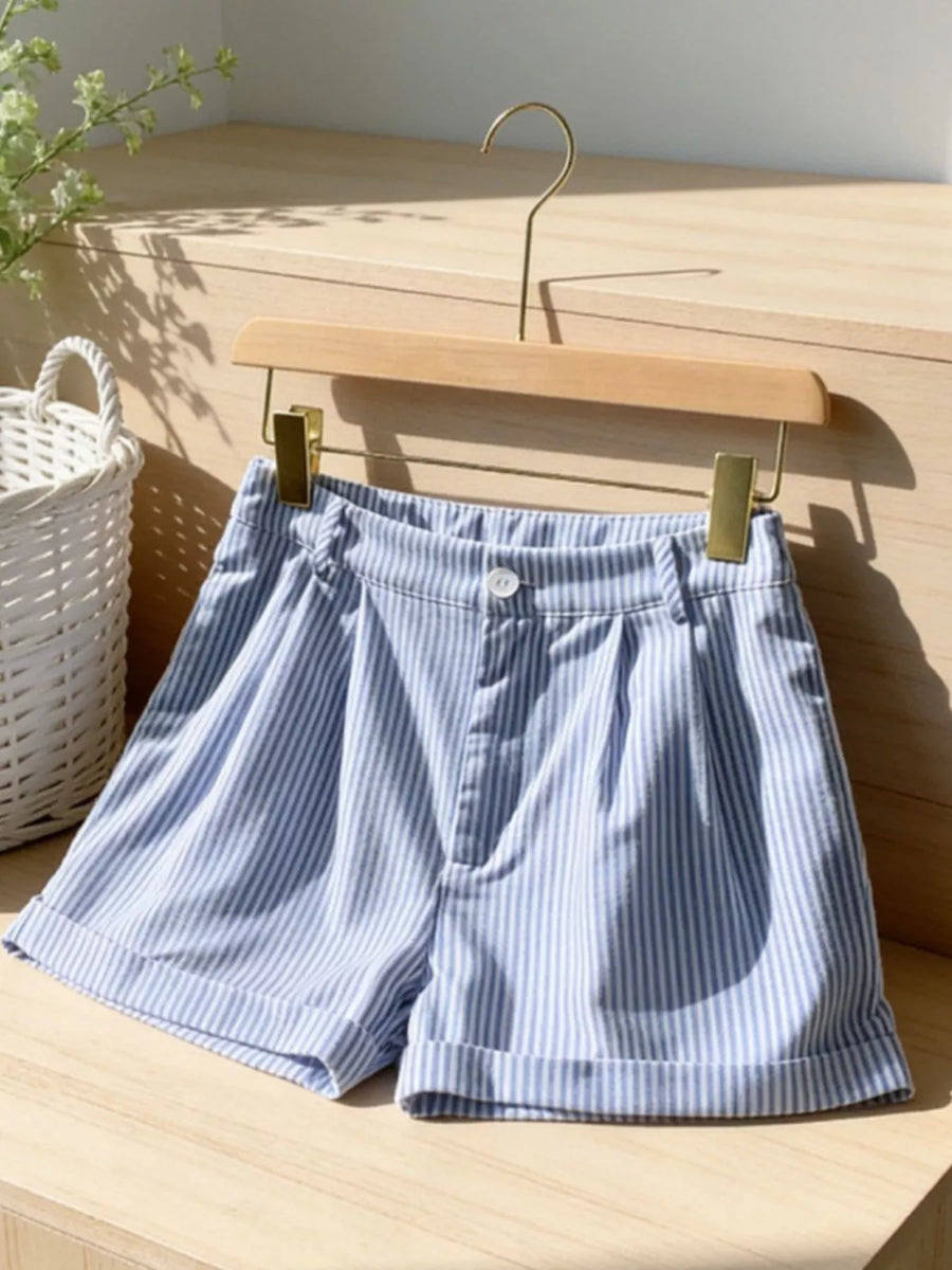 Blue and white striped shorts on a wooden hanger against a wooden background
