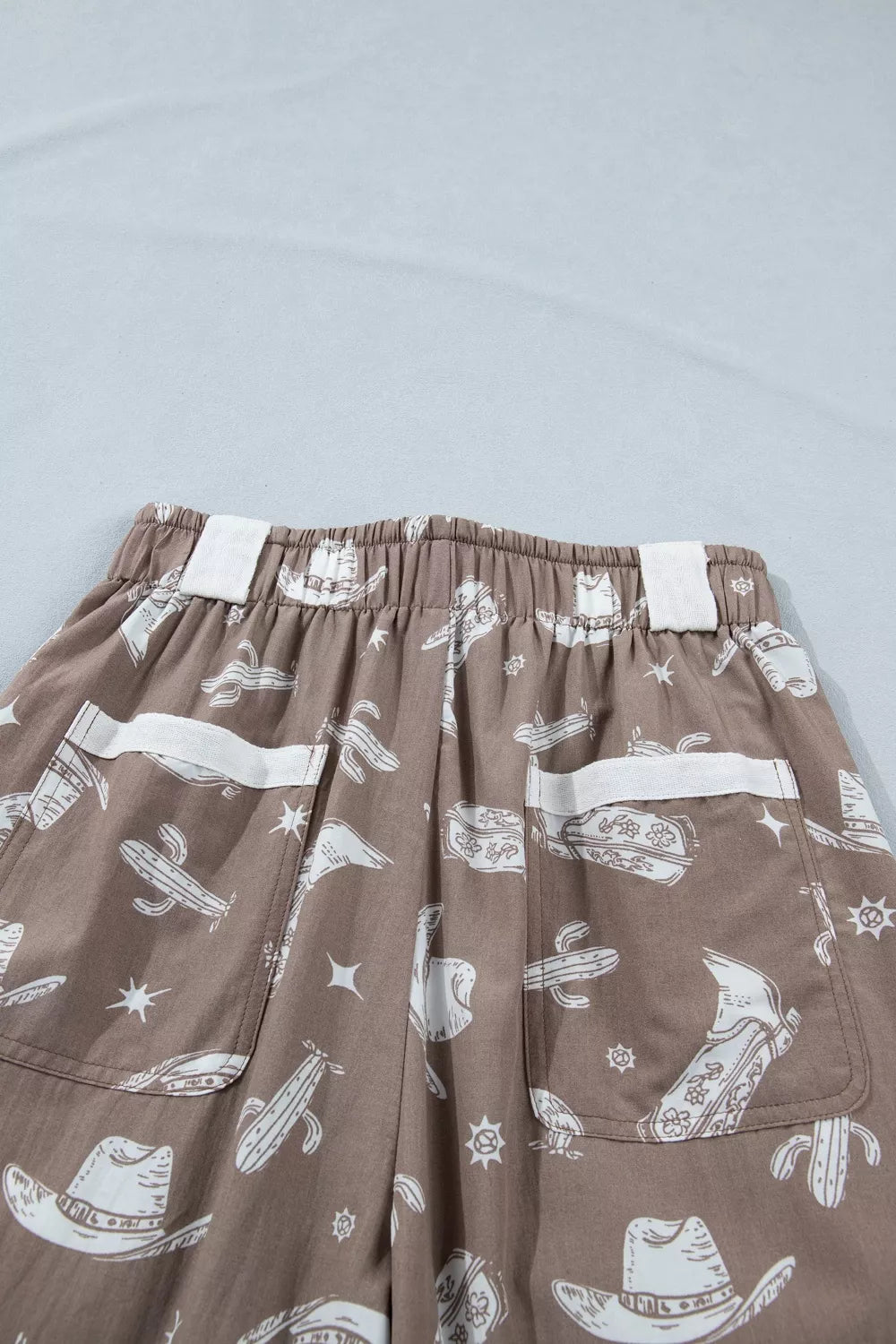 Brown pants with white graphic designs on a light gray background