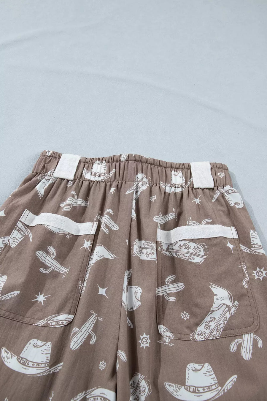 Brown pants with white graphic designs on a light gray background