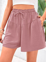 Mauve shorts with a drawstring waist worn by a person on a blurred background