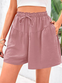 Mauve shorts with a drawstring waist worn by a person on a blurred background