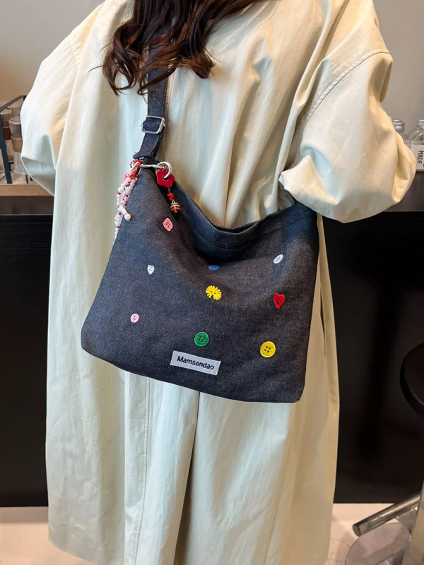 Person wearing a denim bag with colorful embellishments and a visible brand logo.