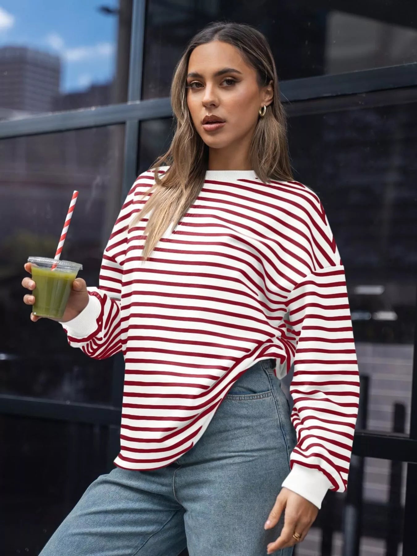 Woman in a red and white striped sweater holding a green smoothie.